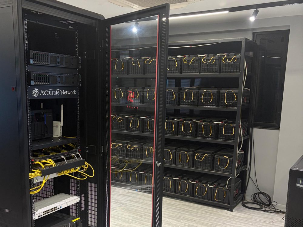 Our server room with a rack and a wall of backup batteries