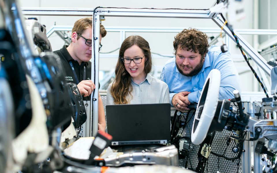 Engineers reviewing a system on a laptop in a workshop